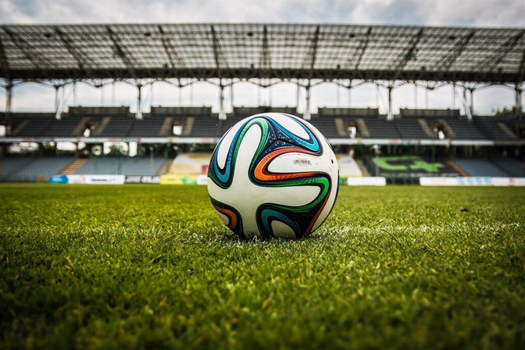 A soccer ball sitting on an empty field within a stadium.